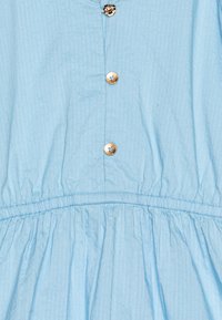 Robe en coton bleu clair avec un devant boutonné, une taille froncée et un tissu texturé avec un motif rayé subtil.