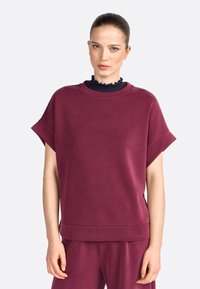 Bordeaux oversized sweatshirt met korte mouwen, ribgebreide halslijn, zachte textuur en een casual pasvorm. Gecombineerd met bijpassende onderkleding.