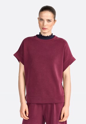 Bordeaux oversized sweatshirt met korte mouwen, ribgebreide halslijn, zachte textuur en een casual pasvorm. Gecombineerd met bijpassende onderkleding.
