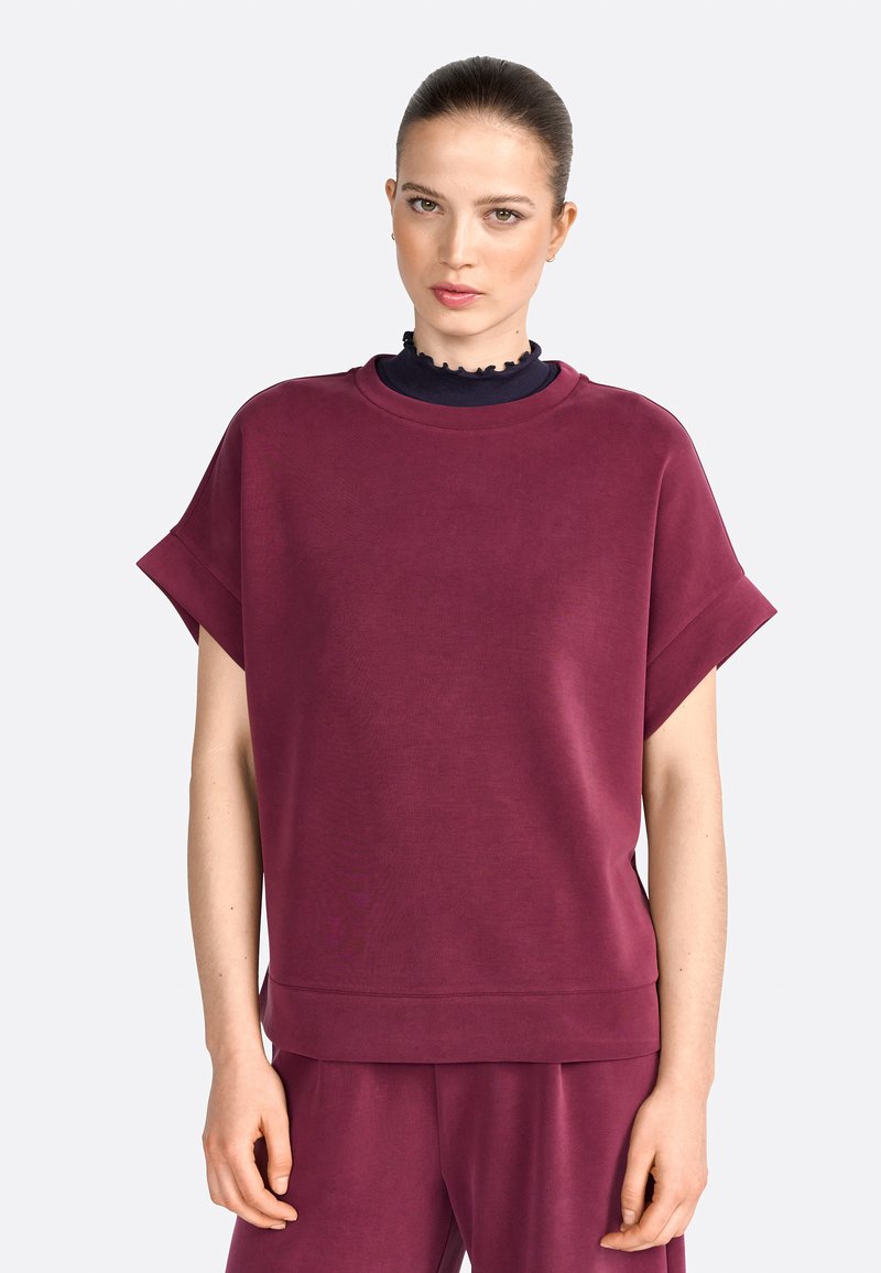 Bordeaux oversized sweatshirt met korte mouwen, ribgebreide halslijn, zachte textuur en een casual pasvorm. Gecombineerd met bijpassende onderkleding.
