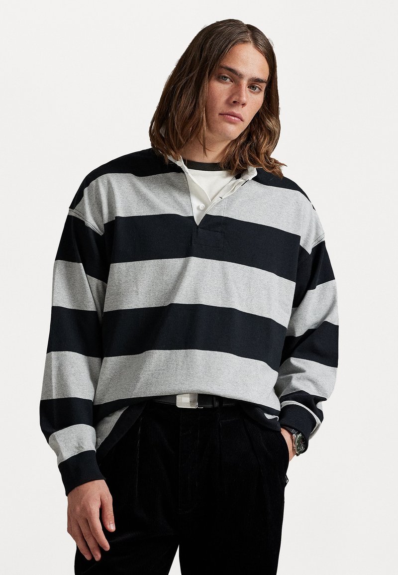 Camisa de rugby de manga larga con rayas alternas en negro y gris, un collar con una parte de la tapeta y un ajuste relajado.