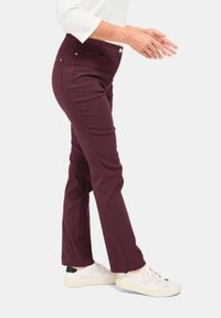 Bordeaux stretchbroek met een slim fit, elastische tailleband en twee achterzakken, gecombineerd met witte sneakers.