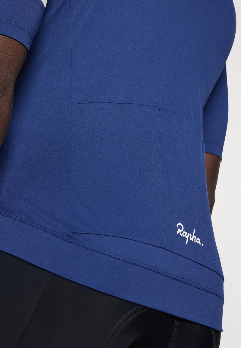 Blå atletisk skjorte lavet af glat materiale, med en side lomme og hvid "Rapha." logo detalje på den nederste front.