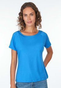 Blaues kurzärmliges T-Shirt mit weitem, rundem Ausschnitt, aus leichtem Stoff; glatte Textur und lockere Passform, gezeigt mit Denim-Shorts.