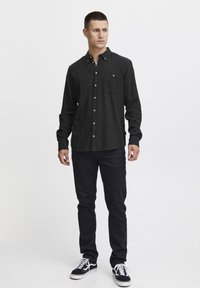 Dark gray button-up shirt with gold buttons, single chest pocket, and long sleeves, paired with dark pants and black shoes.