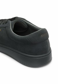 Baskets en daim noir avec design profil bas, semelle noire, laçage à l'avant et détail du logo triangulaire cousu sur le talon.