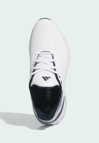 White athletic shoe with a textured leather upper, round toe, lace-up front, and navy blue interior, featuring light branding detail.
