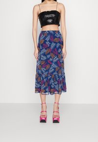 Czarny top z cekinami, niebieska spódnica w różowe i pomarańczowe liście, falbaniasty dół oraz różowe sandały na grubym obcasie z paskami na kostkach.