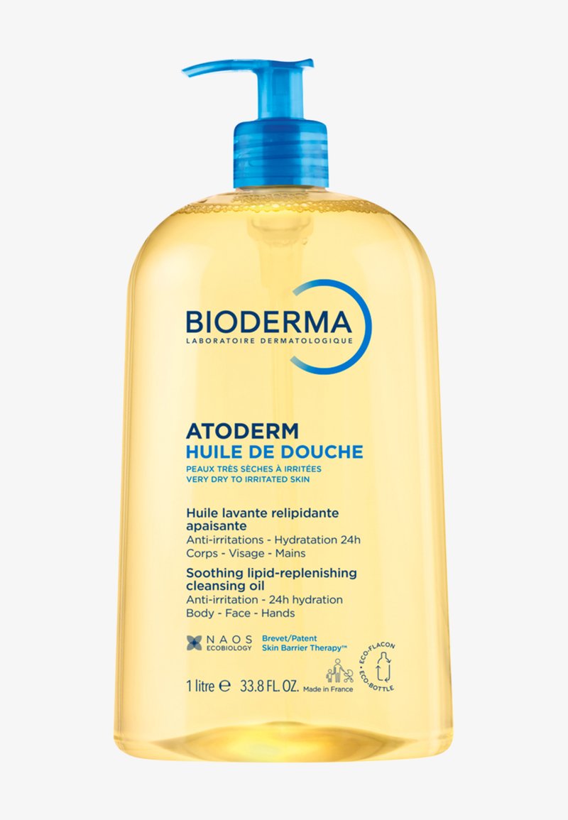 Huile nettoyante Bioderma Atoderm dans un flacon transparent avec pompe. Liquide jaune visible, avec du texte et des accents bleus mettant en valeur les détails du produit.