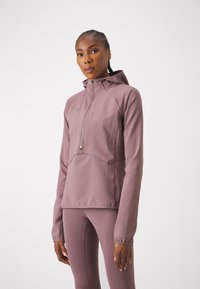 Casaco de felpa em mauve com um design texturizado, fecho zip e capuz ajustável, com punhos elásticos. Combinado com leggings a condizer.