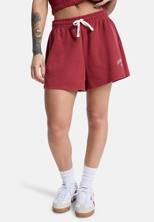 Bordowe bawełniane spodenki z elastycznym pasem i białym sznurkiem do wiązania, z logo po lewej stronie.