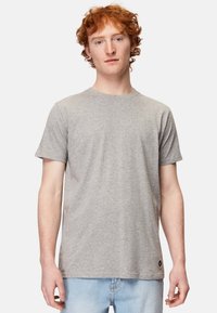 Grå kortærmet t-shirt lavet af bomuld med rund hals, der har et lille logo i nærheden af kanten. Enkel og uprydet design.