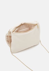 Beige polstrovaná kabelka s hladkým povrchem, zlatým zipem a odnímatelným řetízkem. Interiér má jemnou podšívku a malou kapsu.