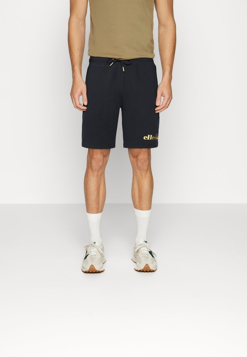 Navy cotton blend shorts with an elastic drawstring waistband and a gold logo on the left leg, paired with white socks and light sneakers.