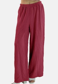 Pantalones de pierna ancha hechos de tela texturizada y arrugada de color rosa intenso, con una pretina elástica y un ajuste relajado.
