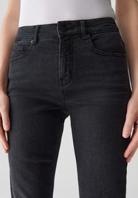 Jeans in denim nero con una silhouette attillata, dotati di tasche anteriori, chiusura con bottone e dettagli di cucitura sottili.