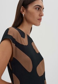 Kurzarmtop mit einem schwarz-braunen abstrakten Muster, aus einem weichen, leichten Stoff mit glatter Textur.