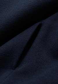 Tessuto di lana blu navy con una superficie morbida e testurizzata. Presenta pieghe delicate che creano profondità e movimento.