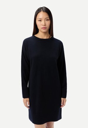 Marineblaues Strickkleid aus weichem Material, mit langen Ärmeln und lockerem Sitz, einem Rundhalsausschnitt und einer Länge bis zur Mitte des Oberschenkels.