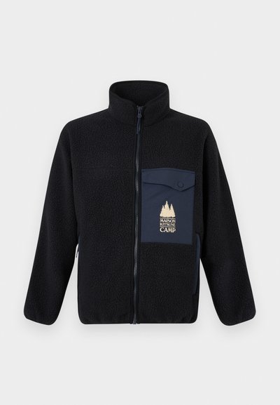 Μαύρο φλις μπουφάν με φερμουάρ μπροστά, ψηλό γιακά και αντίθετο ναυτικό τσέπη στο στήθος με χρυσό κείμενο και σχέδιο δέντρου.