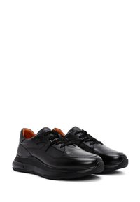 Scarpe sportive nere in pelle testurizzata e materiali sintetici, con punta arrotondata, suola ammortizzata e lacci neri su una fodera interna arancione.