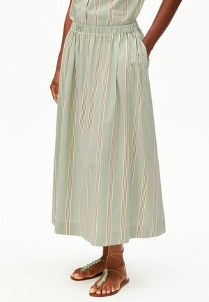 Jupe midi vert clair à rayures verticales beige et marron, taille élastique, poches latérales, portée avec des sandales marron ornées de perles.