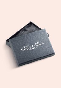 Grå smykkeboks med en struktureret overflade, der har et hvidt krøllet logo "Sofia Milani Jewels" på toppen og en sort indvendig foret.