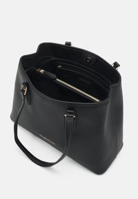 Sac fourre-tout en cuir noir avec surface texturée, deux poignées, accastillage doré et un intérieur spacieux comprenant des poches zippées et des poches plaquées.