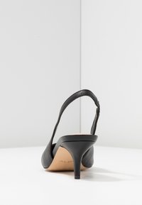 Czarny skórzany but na obcasie typu slingback z zaostrzonym noskiem i smukłym obcasem szpilkowym. Charakteryzuje się minimalistycznym designem i gładką fakturą.