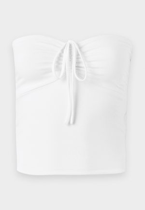 Bela brezramna bluzica s nabranim sprednjim delom, ki ima vrvico za zapiranje na sredini, izdelana iz gladkega, raztegljivega materiala.