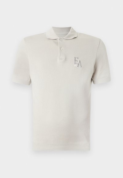 Polo de manga corta color beige claro con dos botones y logo bordado "EA" en el pecho izquierdo.