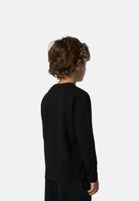 Camisa negra de manga larga hecha de algodón, con un sencillo cuello redondo y un corte relajado. Detalles adicionales incluyen una textura suave y lisa.