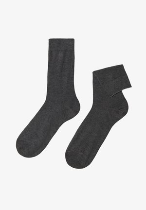 Graue Socken aus weichem Stoff, mit einem gerippten Bündchen und einem glatten, nahtlosen Design. Eine Socke steht aufrecht, die andere ist leicht gerollt.