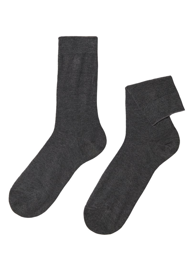 Calze grigie in un tessuto morbido, con un polsino a coste e un design liscio e senza cuciture. Una calza è in posizione verticale, l'altra è leggermente arrotolata.