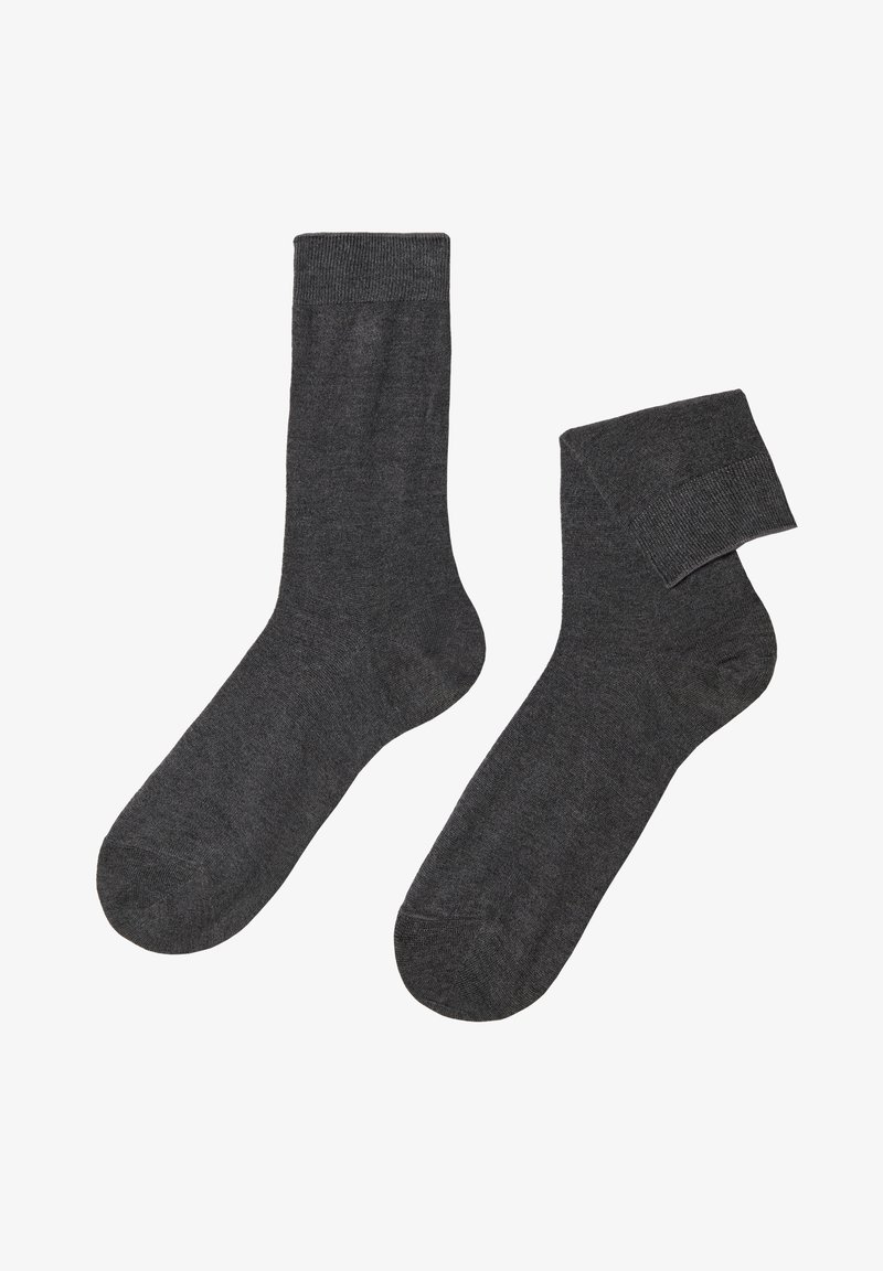 Graue Socken aus weichem Stoff, mit einem gerippten Bündchen und einem glatten, nahtlosen Design. Eine Socke steht aufrecht, die andere ist leicht gerollt.