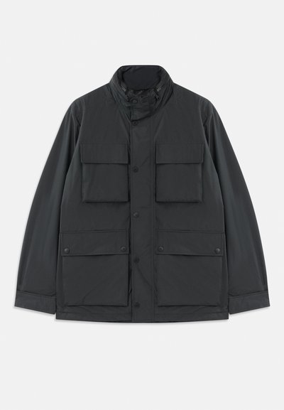 Giacca utility nera con quattro tasche anteriori a patta, chiusura a bottoni a pressione, maniche lunghe e colletto alto con zip.