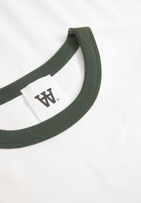 White t-shirt with a dark green ribbed crew neck, featuring a woven label with a logo on the inside collar. Smooth, cotton fabric.