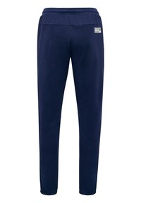 Marineblauwe sportbroek gemaakt van zachte stof. Kenmerken zijn een elastische tailleband, taps toelopende benen en een klein logo-opdriksel op de achterkant.