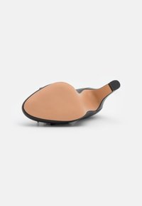 Scarpa nera con tacco alto, design elegante, punta affilata, tomaia in pelle liscia e suola in gomma beige con una leggera texture rigata.