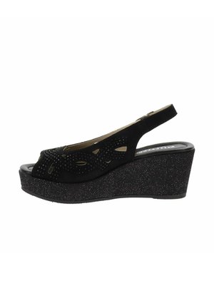 Sandalo con zeppa in suede nero, modello slingback, con design perforato, tacco testurizzato e dettagli borchiati. Soletta imbottita con suola nera uniforme.