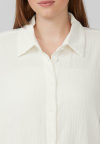 Witte blouse met kraag, gemaakt van gestructureerde stof, met een knoopsluiting aan de voorkant en een zacht gegolfde kraag voor een ontspannen pasvorm.