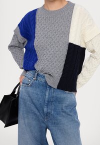 Gebreide trui met een kleurblokontwerp met secties in grijs, blauw, wit en marineblauw. Kabelbreipatroon en geribde manchetten. Gepaard met denim.