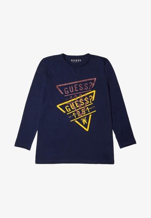 Chemise bleu marine à manches longues avec deux logos triangulaires superposés en rouge et jaune, comprenant le texte "GUESS?" et de petits détails graphiques.