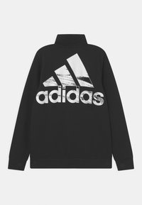 Felpa nera Adidas con colletto alto, maniche lunghe e un grande logo grafico bianco sulla schiena con un aspetto testurizzato e usurato.