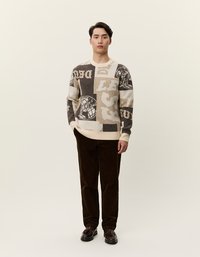 Adatu džemperis ar patchwork dizainu krēmkrāsā, brūnā un melnā, ar dažādiem tekstu modeļiem. Saskaņots ar brūnām korduroja biksēm.