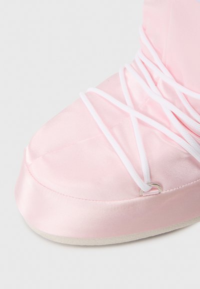 Zapato de ballet de satén rosa con cordones de elastano blancos y punta redondeada. La suela es plana con un acabado texturizado para mayor agarre.