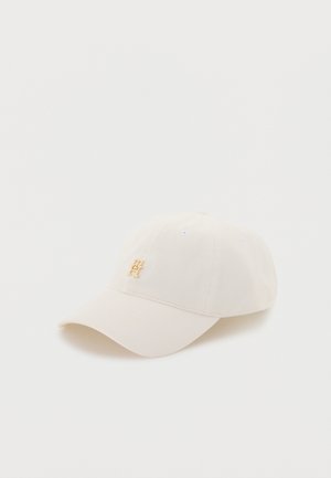 Cappello da baseball bianco con un piccolo logo metallico dorato sul davanti, su sfondo bianco semplice.