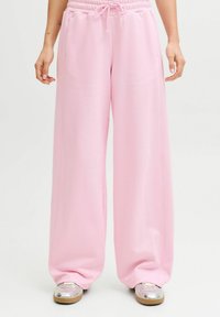 Vaaleanpunaiset, leveälahkeiset collegehousut, jotka on valmistettu pehmeästä kankaasta. Niissä on joustava vyötärönauha ja kiristysnaru sekä sivutaskut.