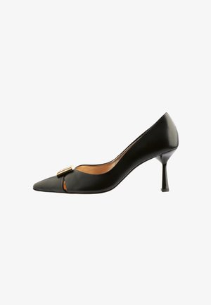 Black leather pump with pointed toe, cut-out design, and gold-tone hardware accent. Features a slender, angular heel, smooth texture.