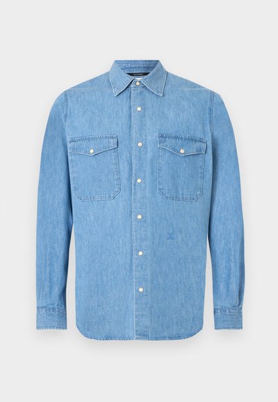 Light blue denim long-sleeve shirt with button-down front and two chest flap pockets with snap buttons on white background.